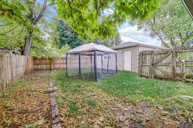 a view of a house with a yard and large tree