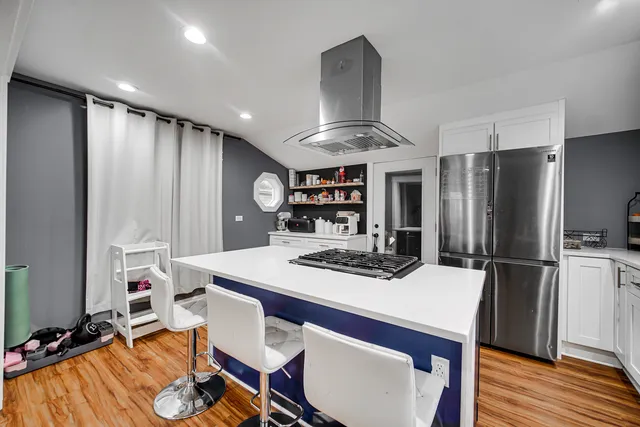 a kitchen with stainless steel appliances kitchen island granite countertop a dining table and chairs