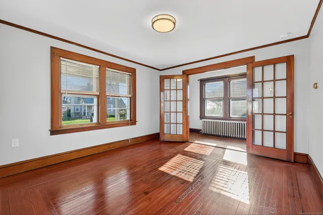 a view of an empty room with a window and wooden floor