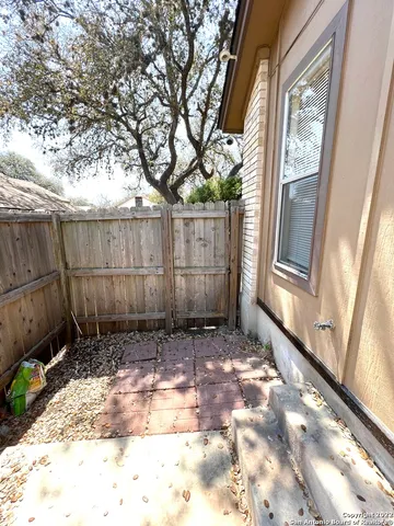 a view of a backyard with wooden fence and a large tree