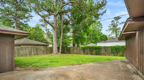 a view of a house with a yard and a large tree