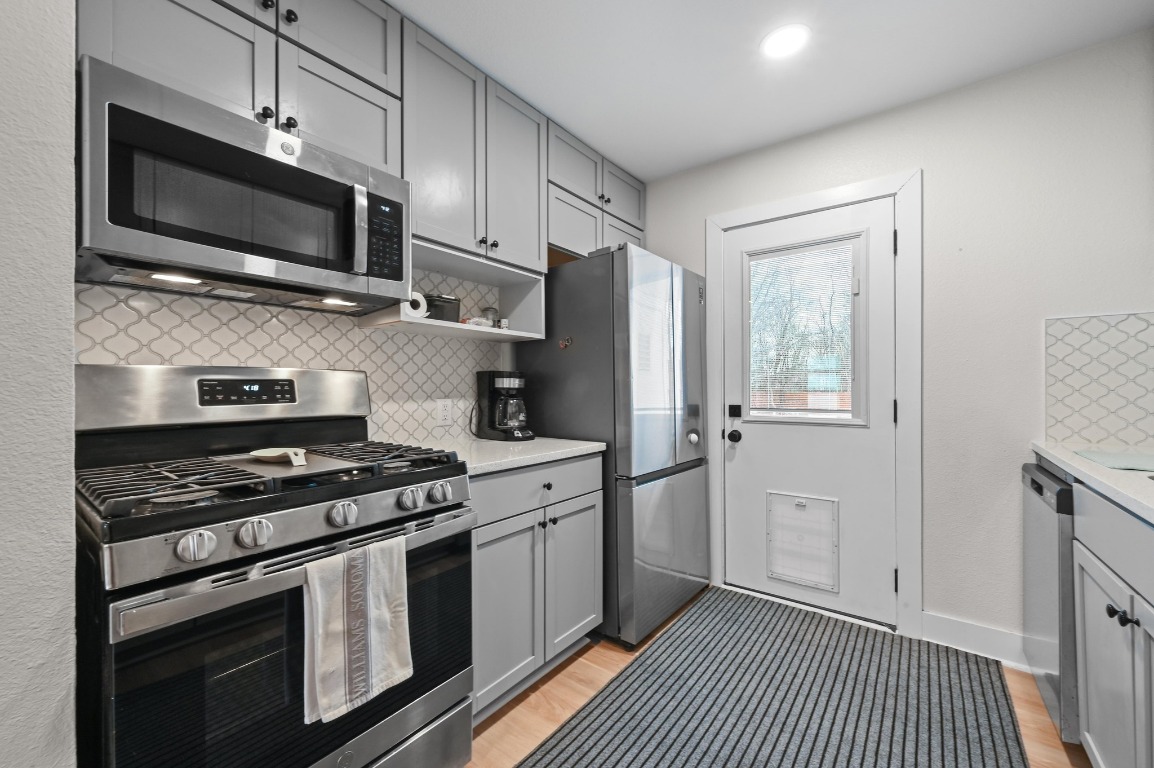 1307 Falcon Cove, Unit A Austin, TX 78745 - Photo 12 of 21 Kitchen with gray cabinetry, stainless steel appliances, decorative backsplash, open shelves, and recessed lighting