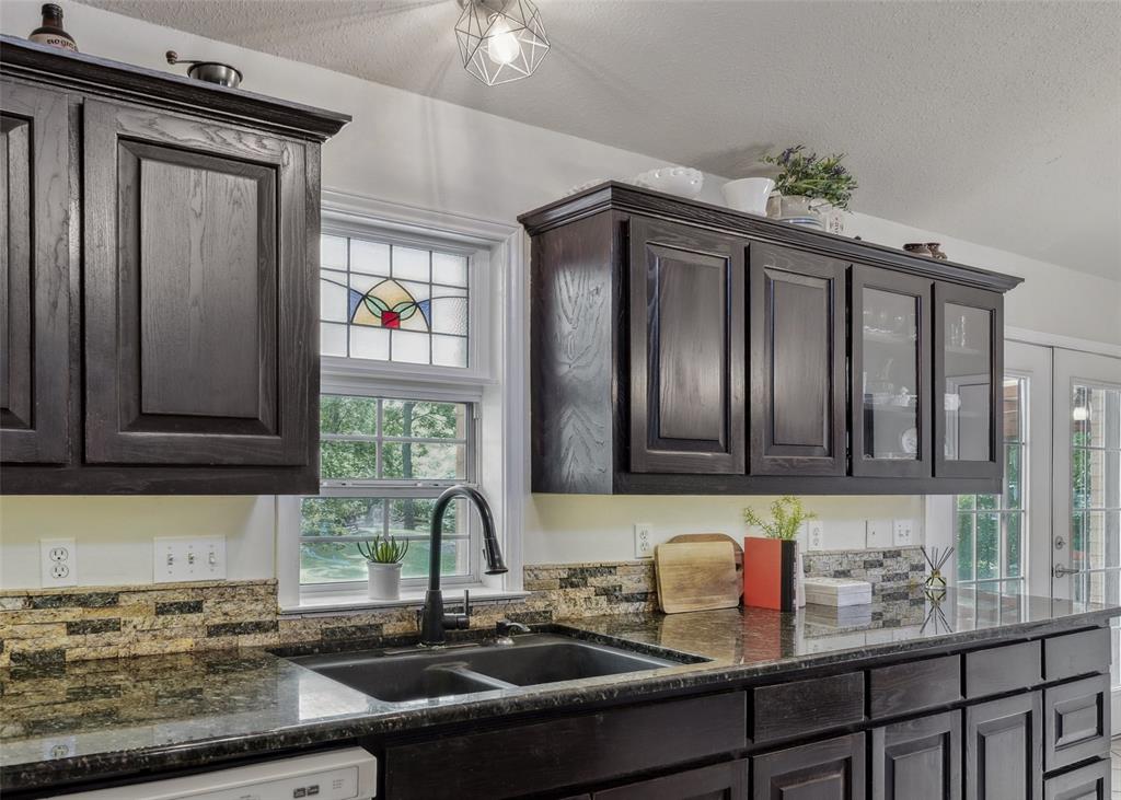 1000 Ballard Road Van Alstyne, TX 75495 - Photo 18 of 40 a kitchen with granite countertop a sink stainless steel appliances wooden floor and cabinets