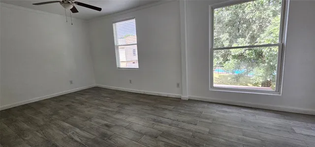 an empty room with wooden floor and windows