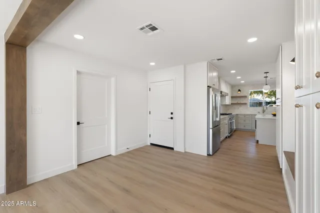 a view of an empty room with wooden floor and a bathroom