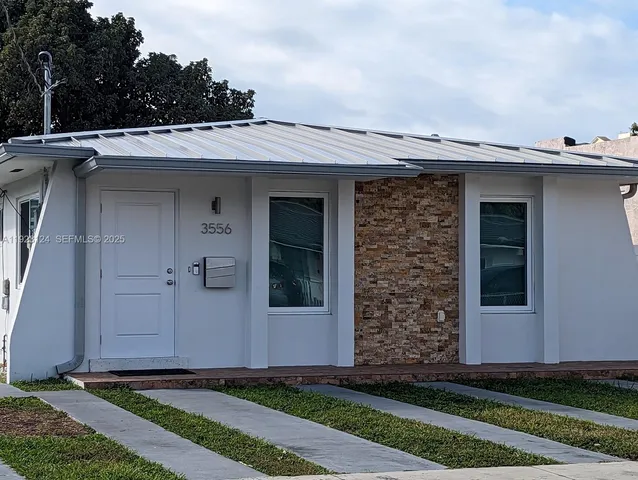 a view of a house with a small yard and wooden floor and fence