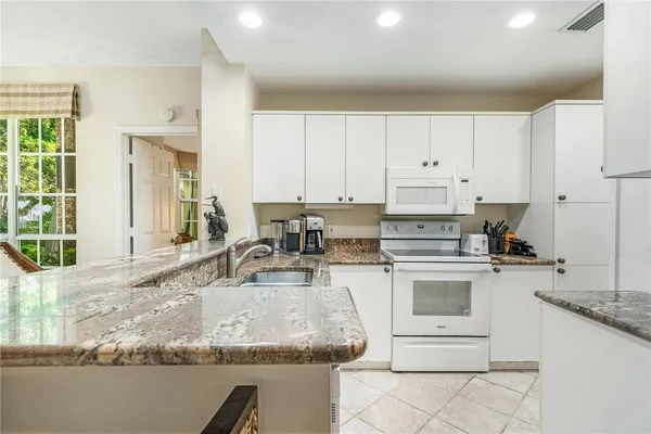 a kitchen with granite countertop a sink stove and white cabinets