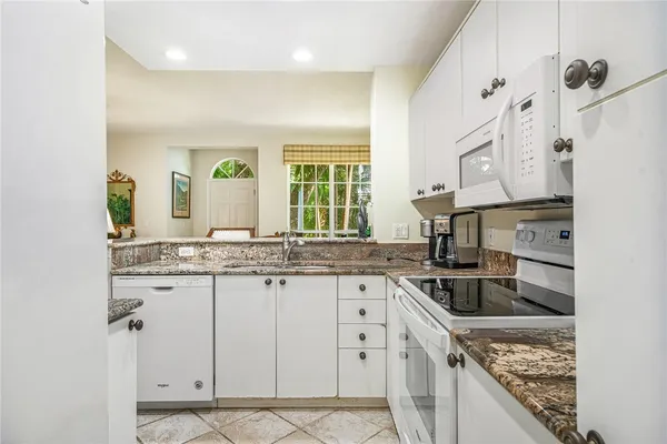 a kitchen with granite countertop a sink stove and cabinets