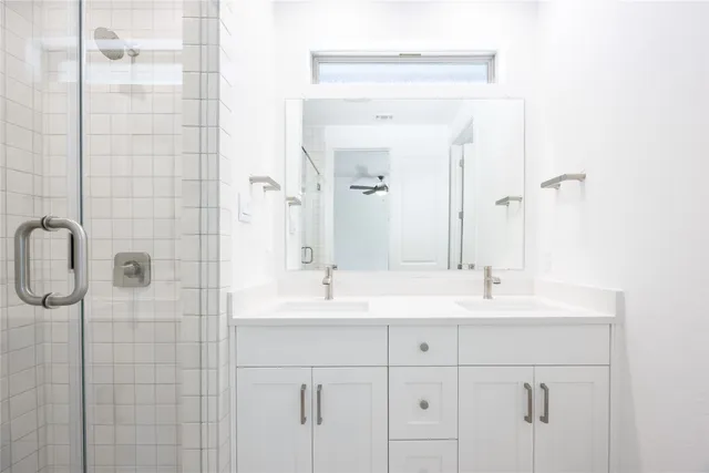 a bathroom with a double vanity sink mirror and shower