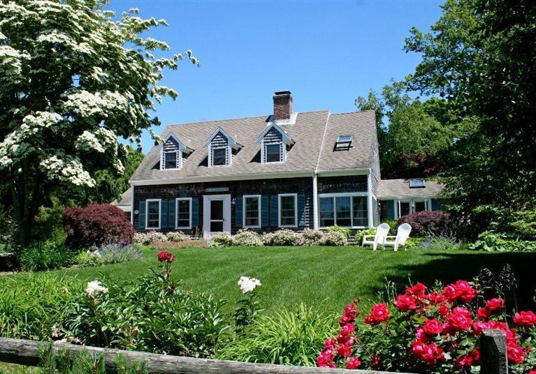 a front view of a house with a big yard and potted plants