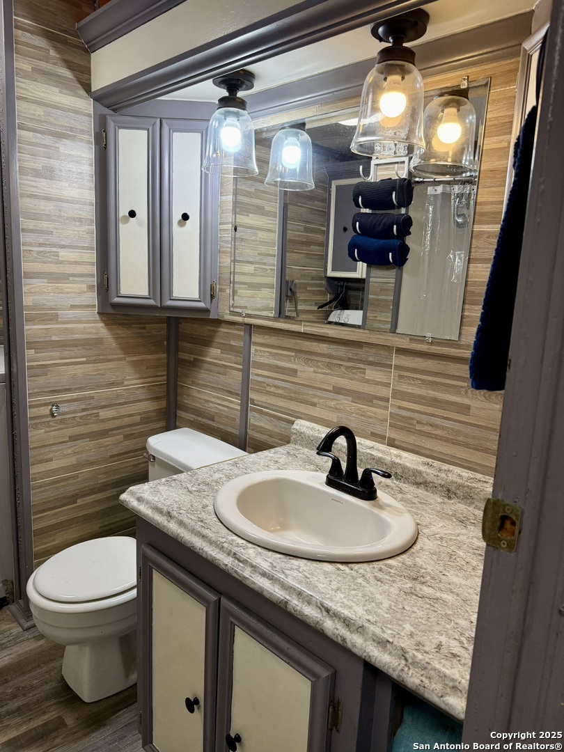 508 East Thornton Street Three Rivers, TX 78071 - Photo 12 of 17 a bathroom with a granite countertop sink a toilet and mirror