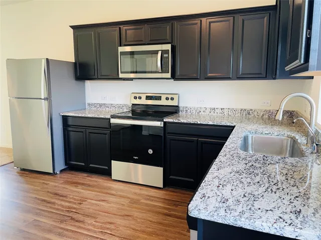 a kitchen with stainless steel appliances granite countertop a sink stove and refrigerator