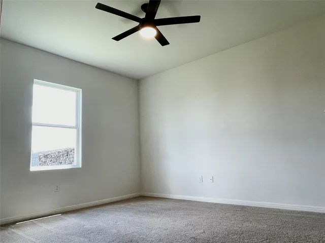 an empty room with a window and a ceiling fan