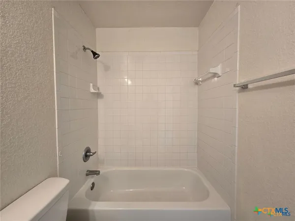 a bath tub sitting next to a white toilet and a shower