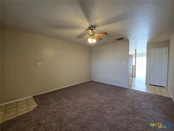 an empty room with a chandelier fan and windows