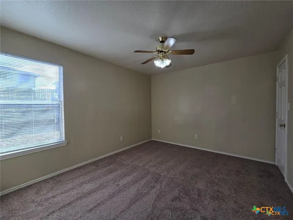 an empty room with a window and ceiling fan