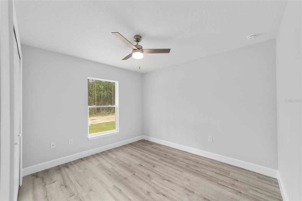 6832 Southwest 153rd Pl Road Ocala, FL 34473 - Photo 22 of 31 an empty room with wooden floor ceiling fan and windows