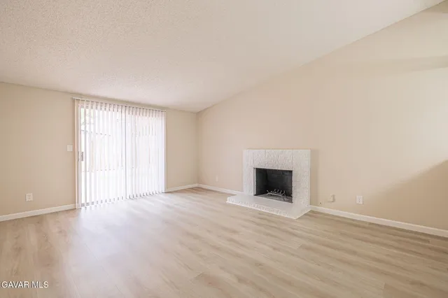 an empty room with wooden floor fireplace and windows