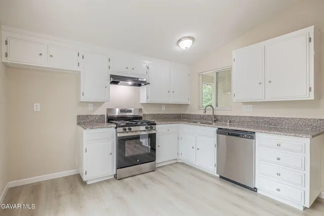 a kitchen with granite countertop white cabinets and stainless steel appliances