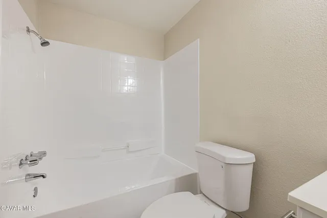 a white toilet sitting next to a bath tub