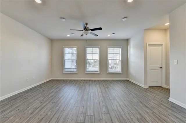 a view of an empty room with a window and wooden floor
