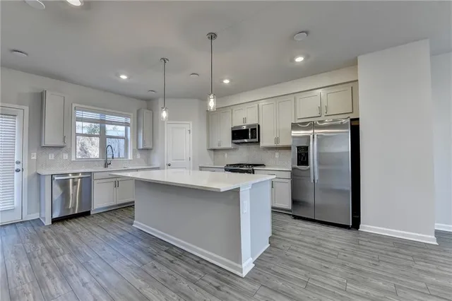 a large kitchen with cabinets wooden floor and stainless steel appliances