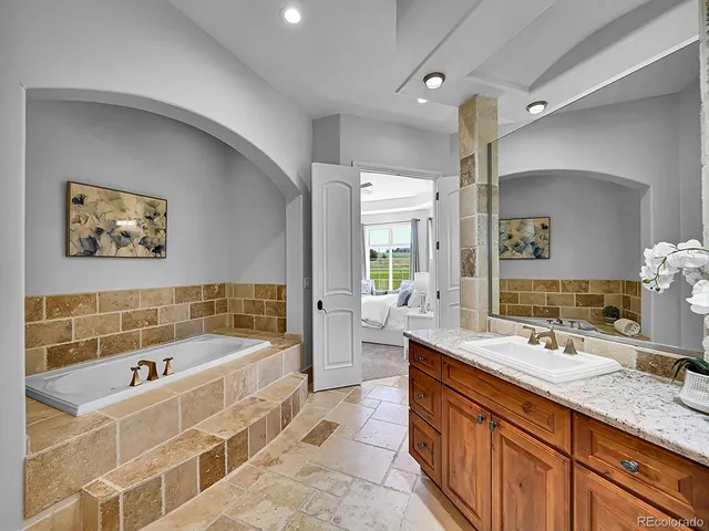 a bathroom with a tub a double vanity sink and mirror