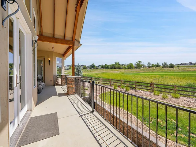a view of a balcony with wooden floor & fence next to a yard