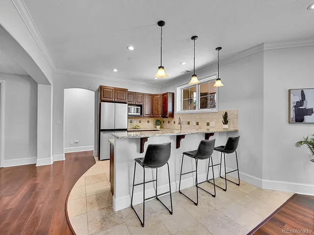 a kitchen with stainless steel appliances kitchen island granite countertop a table chairs and a wooden floor