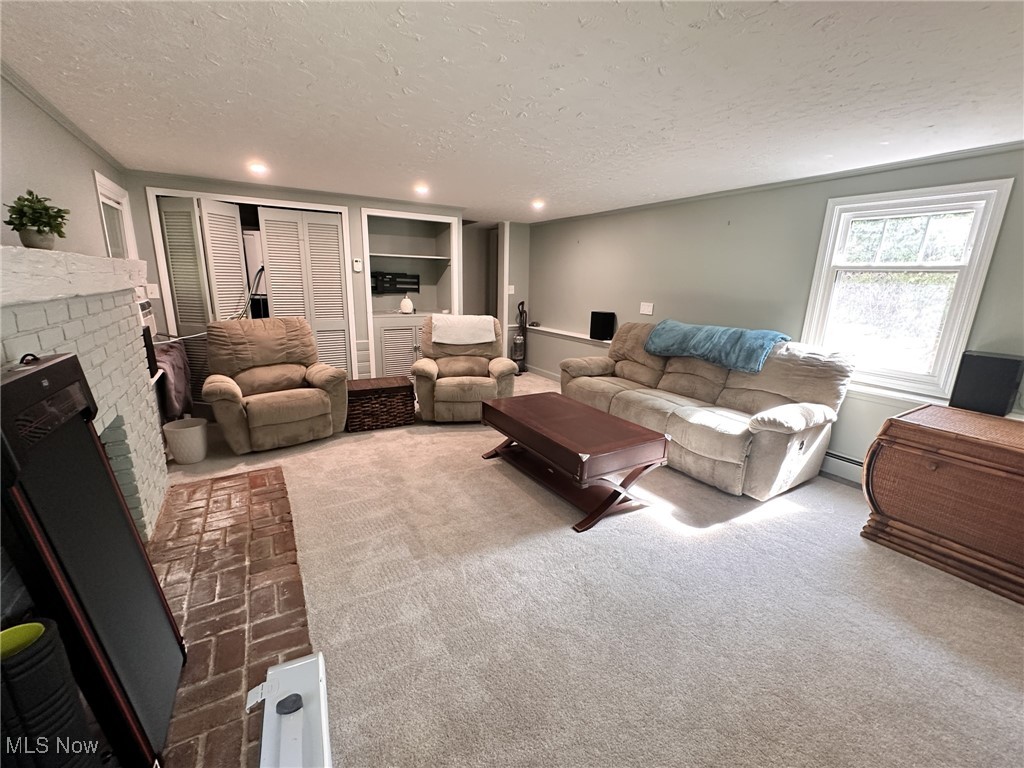 8145 Chagrin Road Chagrin Falls, OH 44023 - Photo 32 of 40 Living room featuring a brick fireplace, carpet, a textured ceiling, and a baseboard radiator