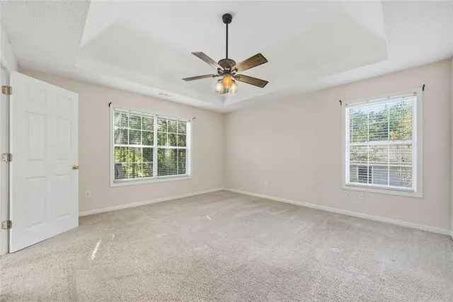 a view of an empty room with window and a ceiling fan