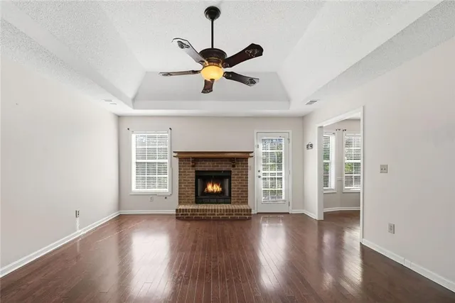 a view of an empty room with wooden floor fireplace and a window
