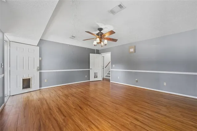 a view of an empty room with a window and wooden floor