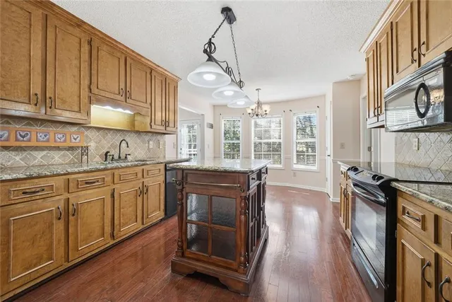 a kitchen with kitchen island granite countertop a sink cabinets and stainless steel appliances