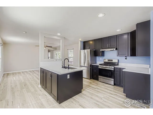 a kitchen with stainless steel appliances granite countertop a stove top oven a sink dishwasher and a refrigerator