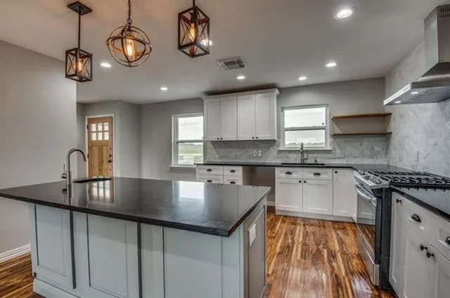 a large kitchen with stainless steel appliances granite countertop a sink and dishwasher a stove top oven with wooden floor