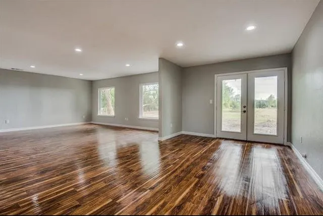a view of an empty room with glass door and wooden floor