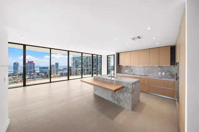 a large white kitchen with granite countertop a large window and a sink