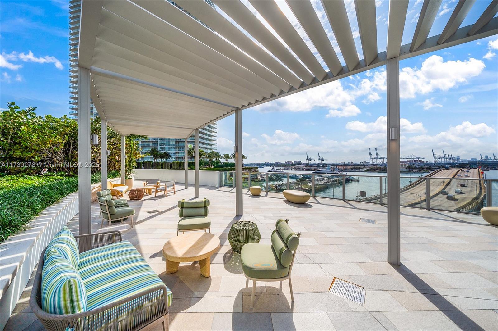 500 Alton Road, Unit 3101 Miami Beach, FL 33139 - Photo 51 of 53 a view of a swimming pool with a couches and chairs under an umbrella with a patio