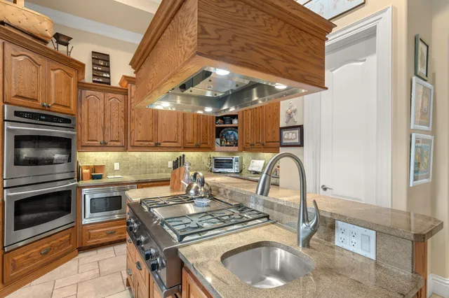 a kitchen with granite countertop a sink a stove and a wooden cabinets