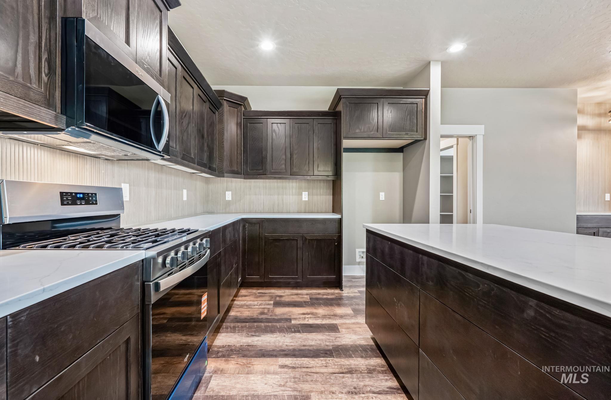 2755 Cypress Point Payette, ID 83661 - Photo 11 of 28 Kitchen featuring appliances with stainless steel finishes, dark brown cabinetry, dark wood-style floors, light stone counters, and recessed lighting