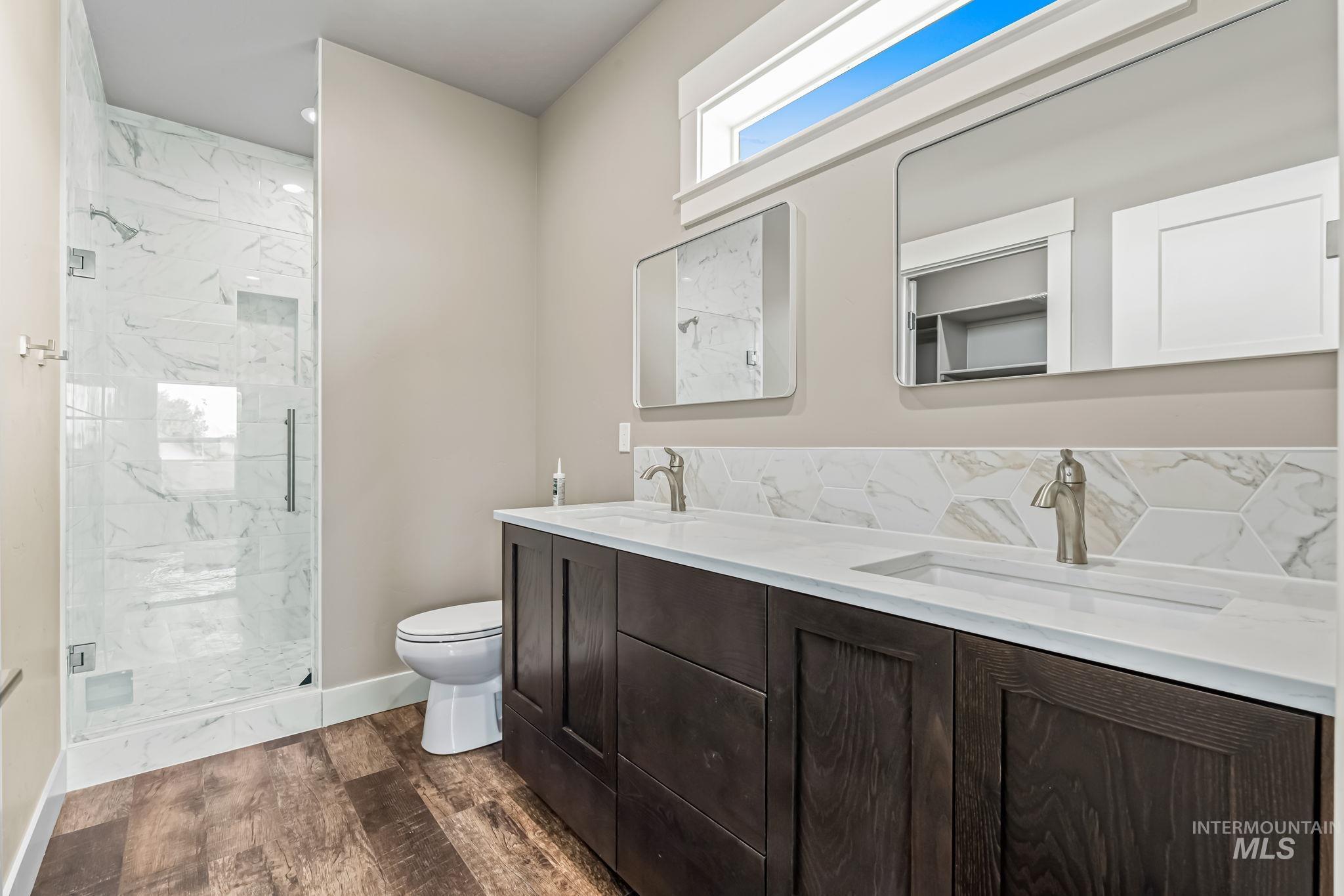 2755 Cypress Point Payette, ID 83661 - Photo 17 of 28 Full bathroom featuring dark wood-style floors, a marble finish shower, double vanity, and backsplash