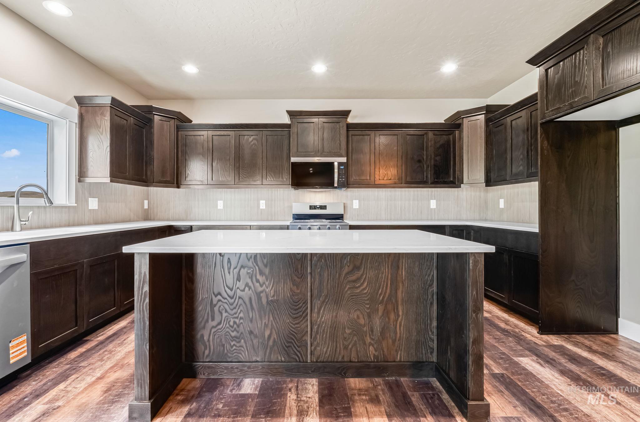 2755 Cypress Point Payette, ID 83661 - Photo 9 of 28 Kitchen with dark brown cabinetry, a center island, stainless steel appliances, backsplash, and recessed lighting