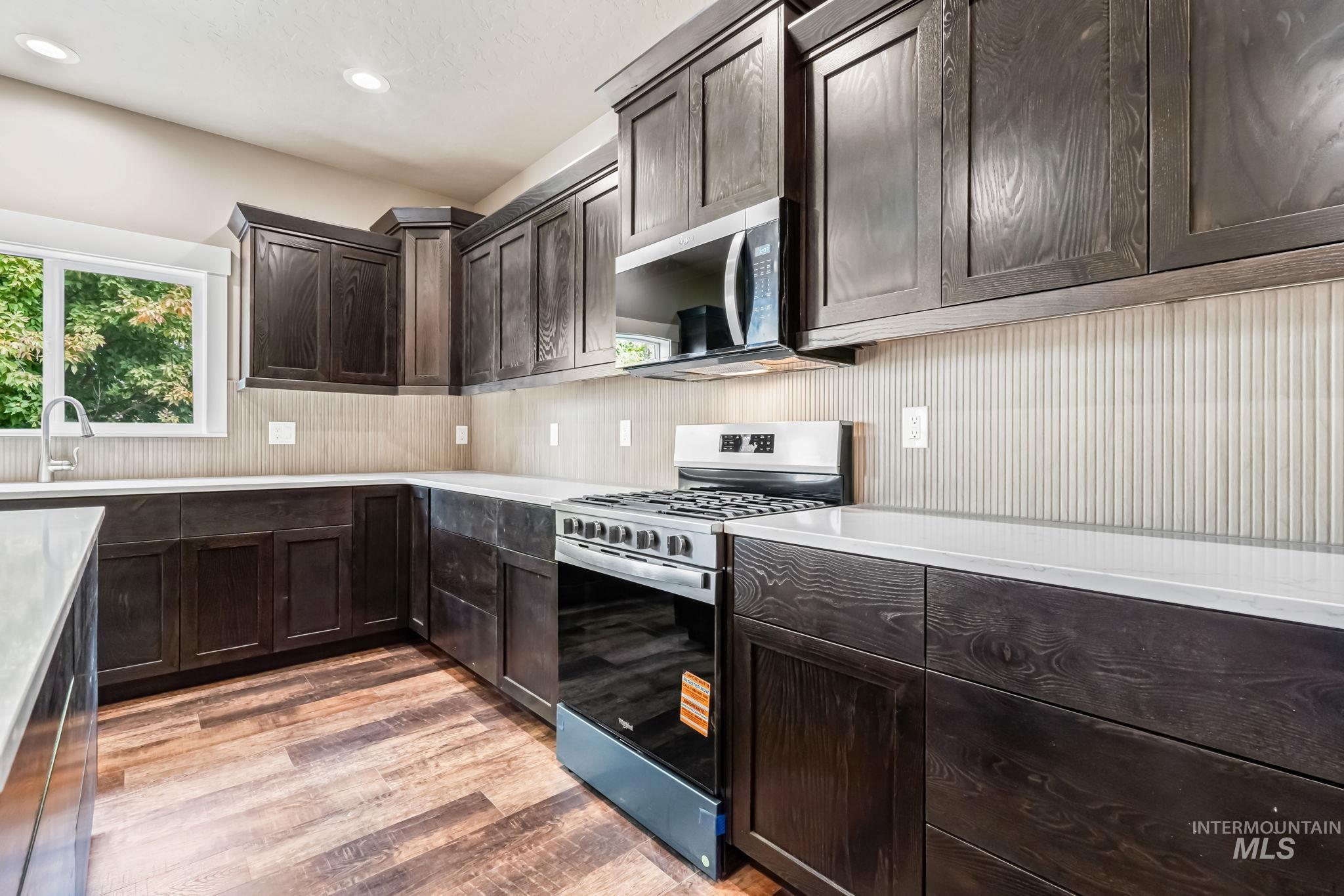 2755 Cypress Point Payette, ID 83661 - Photo 10 of 28 Kitchen with dark brown cabinets, appliances with stainless steel finishes, light wood finished floors, recessed lighting, and light stone countertops