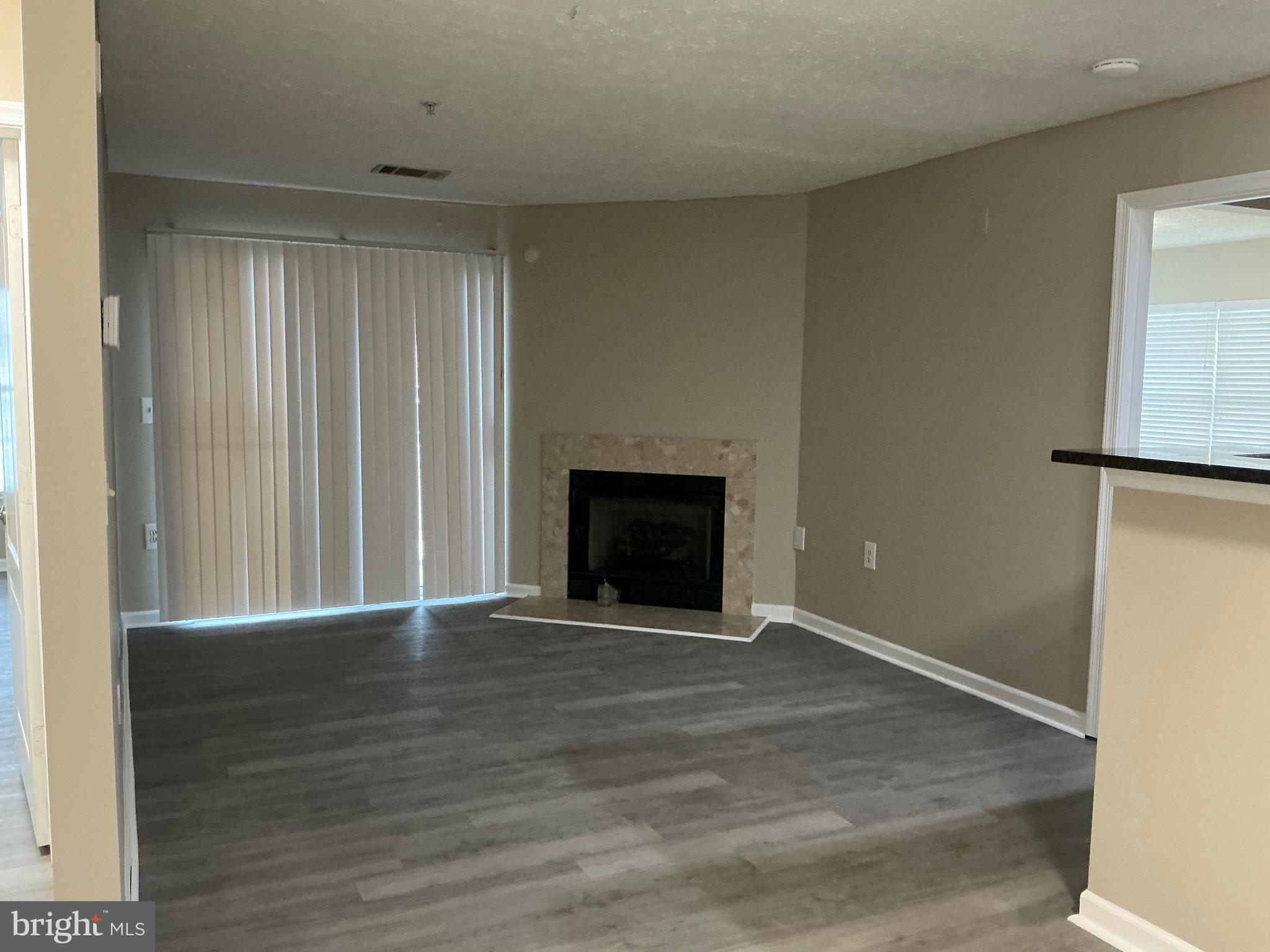 8961 Town Center Circle, Unit 1101 Upper Marlboro, MD 20774 - Photo 7 of 10 an empty room with wooden floor fireplace and windows