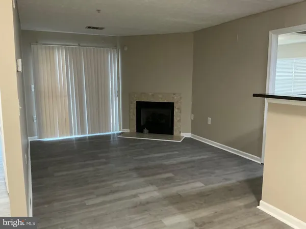 an empty room with wooden floor fireplace and windows