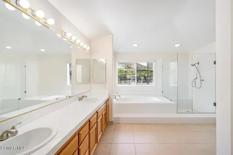 a spacious bathroom with a double vanity sink a mirror and a bathtub