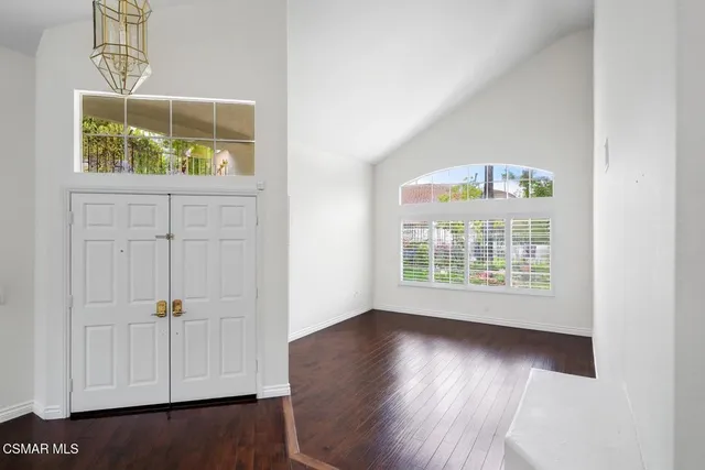 an empty room with wooden floor cabinet and windows
