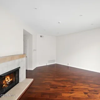 a view of an empty room with wooden floor fireplace and a window