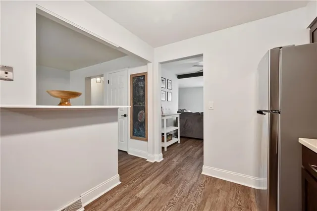 a view of a kitchen from the hallway with a wooden floor and a living room